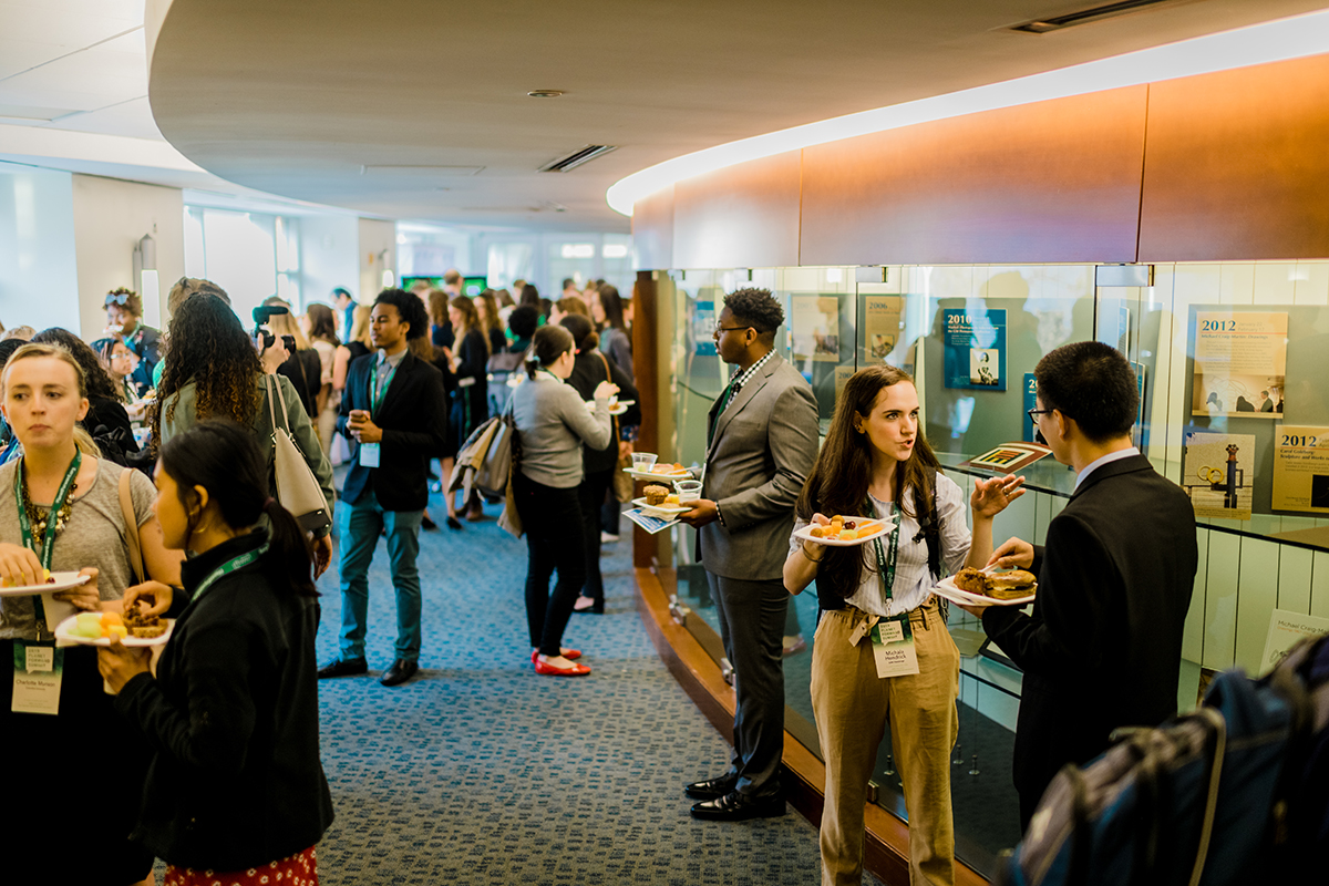 Students, speakers, professor, and professionals gather upstairs during a networking break.